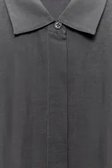 Vestido midi de corte camisero color gris, confeccionado con mezcla de lyocell y lino. Presenta cuello solapa, manga corta, pliegues en la cintura y cierre frontal con botones ocultos.