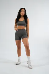 Conjunto deportivo gris compuesto por un top corto con tirantes finos y unos shorts ajustados de tiro alto.
