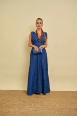 Vestido largo azul con textura arrugada, escote en V pronunciado, sin mangas y falda de corte evasé.