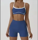 Conjunto deportivo compuesto por un top y un short de tiro alto en color azul con detalles de líneas blancas. El top presenta breteles finos y diseño ergonómico, mientras que el short es ajustado y cuenta con costuras laterales decorativas.