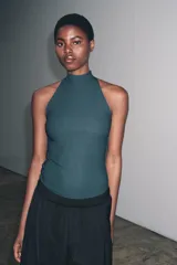 Top negro de cuello halter con cierre de botones en la parte trasera del cuello y espalda descubierta.