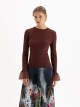 Top de tejido de punto fino color marrón, con cuello redondo, ajuste al cuerpo y mangas largas que terminan en un volante acampanado de tejido calado semitransparente.