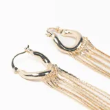 Par de caravanas tipo argolla con diseño de flecos largos compuestos por múltiples cadenas finas colgantes en tono dorado.