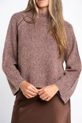 Sweater de tejido de punto con cuello alto, mangas largas y diseño holgado. Presenta un patrón de rayas verticales en tonos malva y beige.