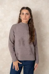 Buzo de punto color visón con cuello alto, manga larga y diseño holgado. Presenta un bordado floral en relieve al tono en la parte frontal.