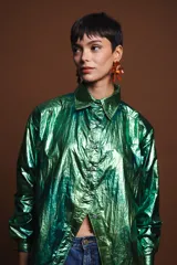 Camisa verde metalizada de corte holgado con cuello clásico, cierre frontal con botones y mangas largas.