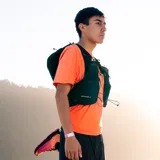 Mochila chaleco de hidratación Merrell en color negro, diseñada para running y trail running, con múltiples bolsillos frontales, cordones de ajuste y tejido de malla transpirable.