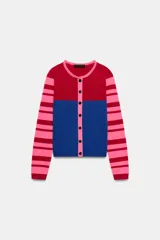 Chaqueta de punto con cuello redondo y manga larga. Presenta un diseño color block con el pecho en rojo, la parte inferior en azul y mangas a rayas horizontales en rosa y rojo. Cierre frontal con botones.