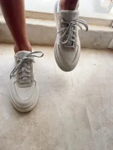 Championes blancos de cuero con cordones y apliques metálicos.