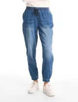 Pantalón tipo jogger de denim azul con efecto lavado. Presenta cintura elástica con cordón ajustable, bolsillos laterales y traseros, y puños elásticos en los tobillos.