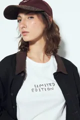 Remera blanca de manga corta con cuello redondo, aberturas laterales y bordado frontal con la frase "LIMITED EDITION" en negro.