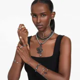 Brazalete rígido abierto bañado en rutenio con motivo de cisne elaborado con cristales Swarovski ReCreated™ negros y cristal transparente en engaste de garra.