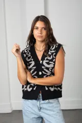 Chaleco tejido sin mangas con escote en V y cierre frontal de botones. Presenta un diseño estampado en contraste de color negro y gris, con un corte holgado y estilo oversize.