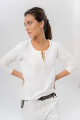 Remera manga larga color beige melange, confeccionada en algodón con spandex, con escote redondo y cartera delantera con botones y detalle de cordón tejido multicolor.