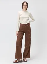 Pantalón de tiro medio y pierna ancha confeccionado en denim de algodón grueso. Presenta un diseño a rayas verticales en tonos azul y celeste, con costuras en contraste color rojo, bolsillos laterales tipo cargo y remaches metálicos.