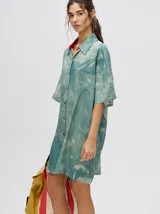 Vestido camisero corto oversize de viscosa con estampado tie-dye en tonos verde agua y blanco, cuello camisero, mangas cortas y bolsillo aplicado en el pecho.