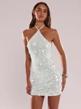 Vestido corto plateado de lentejuelas con escote halter y diseño ajustado.