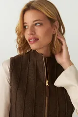 Chaleco corto entallado de lana fina sin teñir, color marrón claro jaspeado, con cierre frontal y alforzas verticales en delantera y espalda.