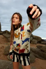 Sweater de lana tejido a mano color crudo, con cuello redondo y puños negros. Presenta bordados de figuras abstractas en colores rojo, azul, amarillo, verde y naranja.