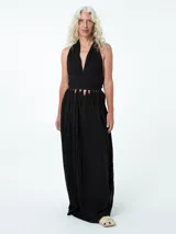 Vestido largo negro de algodón, con escote halter y espalda descubierta. Presenta corte en la cintura con aberturas triangulares.