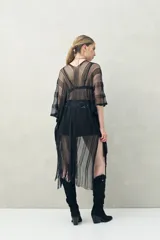 Poncho negro de tejido calado con flecos en el ruedo.