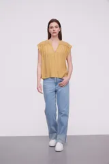 Blusa sin mangas de corte holgado, confeccionada en tela de viscosa con estampado de rayas verticales en tonos mostaza y blanco. Presenta cuello en V profundo y detalles bordados en los hombros.