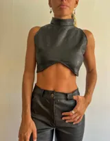 Top negro de cuero sintético con textura de cocodrilo, cuello alto y corte irregular en el abdomen.
