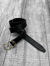 Cinto negro de cuero sintético con hebilla doble circular dorada.