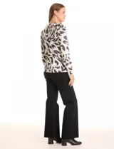 Buzo de hilado fino color blanco con estampado animal print en negro y gris. Cuello redondo, manga larga y detalle de botones dorados en los laterales.