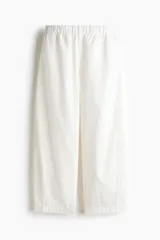 Pantalón tobillero en denim de algodón con cintura elástica y bolsillos al bies, de corte holgado con piernas barrel y costuras laterales avanzadas.