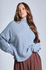 Sweater color crema con cuello alto y diseño de trenzas.