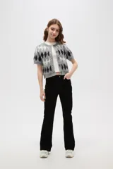 Cardigan de punto con diseño de rombos en tonos gris, blanco y negro. Presenta cuello redondo, cierre frontal con botones y mangas cortas.