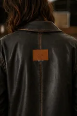 Blazer de cuero vacuno en color negro con efecto envejecido. Presenta una silueta relajada, cuello con solapas, cierre frontal con botones grandes y bolsillos utilitarios con solapa en el frente.