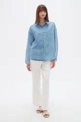 Campera de jean de corte holgado, con cuello camisero, cierre frontal con botones metálicos y mangas largas.