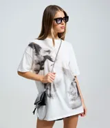 Remera boxy de algodón color blanco, con cuello redondo, mangas cortas y estampa artística de ángeles en escala de grises.