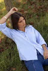 Camisa de lino color celeste, con cuello clásico, cierre frontal de botones y detalle de cuatro estrellas bordadas en color amarillo sobre el pecho. Presenta mangas tres cuartos con detalle de encaje en los puños.