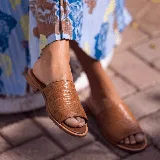 Sandalias chatas de cuero marrón con textura símil cocodrilo, de diseño destalonado y tira ancha sobre el empeine.