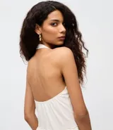 Blusa de algodón color blanco con diseño frente única, bretel posterior y ruedo con volado peplum que aporta volumen. Presenta un corte ajustado en el torso y silueta moderna.