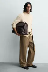 Bolso bandolera de piel color marrón oscuro, con solapa y cierre de imán y cremallera. Incluye un bolsillo interior con cremallera y un bolsillo plano. Tiene asa de hombro ajustable.