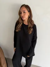 Buzo de cuello redondo y manga larga, confeccionado en tejido de viscosa con textura acanalada en color marrón chocolate. Presenta un corte holgado y relajado.