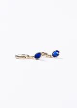 Aros tipo argolla de baño en oro 18k con dije colgante de piedra facetada de color azul intenso.