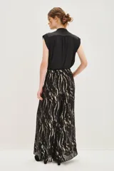 Pantalon de corte amplio y fluido con estampado de cebra en tonos negro y dorado metalizado. Presenta cintura alta y forro interior.
