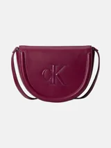 Cartera saddle Calvin Klein de diseño estructurado en color bordó, con solapa superior, cierre magnético, tirante ajustable para el hombro y logo monograma grabado en el frente.