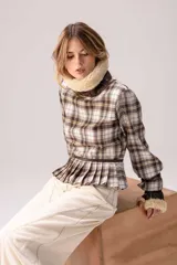 Blusa de tartán con diseño versátil, confeccionada en tela escocesa con detalles en cuero de oveja. Presenta cuello alto con forro de piel sintética, mangas largas con puños de cuero y piel, y un ruedo tableado con ajuste de cinturón de cuero en la cintura.