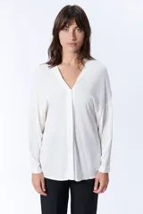 Blusa blanca de manga larga con escote en V y cierre frontal con botones.