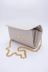 Cartera tipo sobre color beige con textura granulada y correa de cadena dorada.