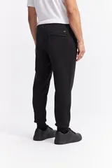 Pantalón de jogging color gris melange, confeccionado en tejido de algodón y poliéster. Presenta cintura elástica con cordón de ajuste, bolsillos laterales con cierre y puños elásticos en los tobillos.