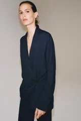 Blazer de corte fluido confeccionada en mezcla de viscosa, con cuello solapa, manga larga con puños abotonados y cierre frontal cruzado con botón único.
