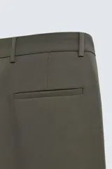 Pantalón de corte relajado en color verde militar, con diseño de pliegues frontales, bolsillos laterales y cierre de cremallera con botón.