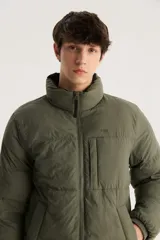 Campera puffer verde militar con cuello alto, cierre frontal con cremallera y bolsillo pequeño en el pecho.